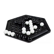 Abalone társasjáték fekete hatszögletű táblán, fehér és fekete golyókkal stratégiai játékmenet közben,