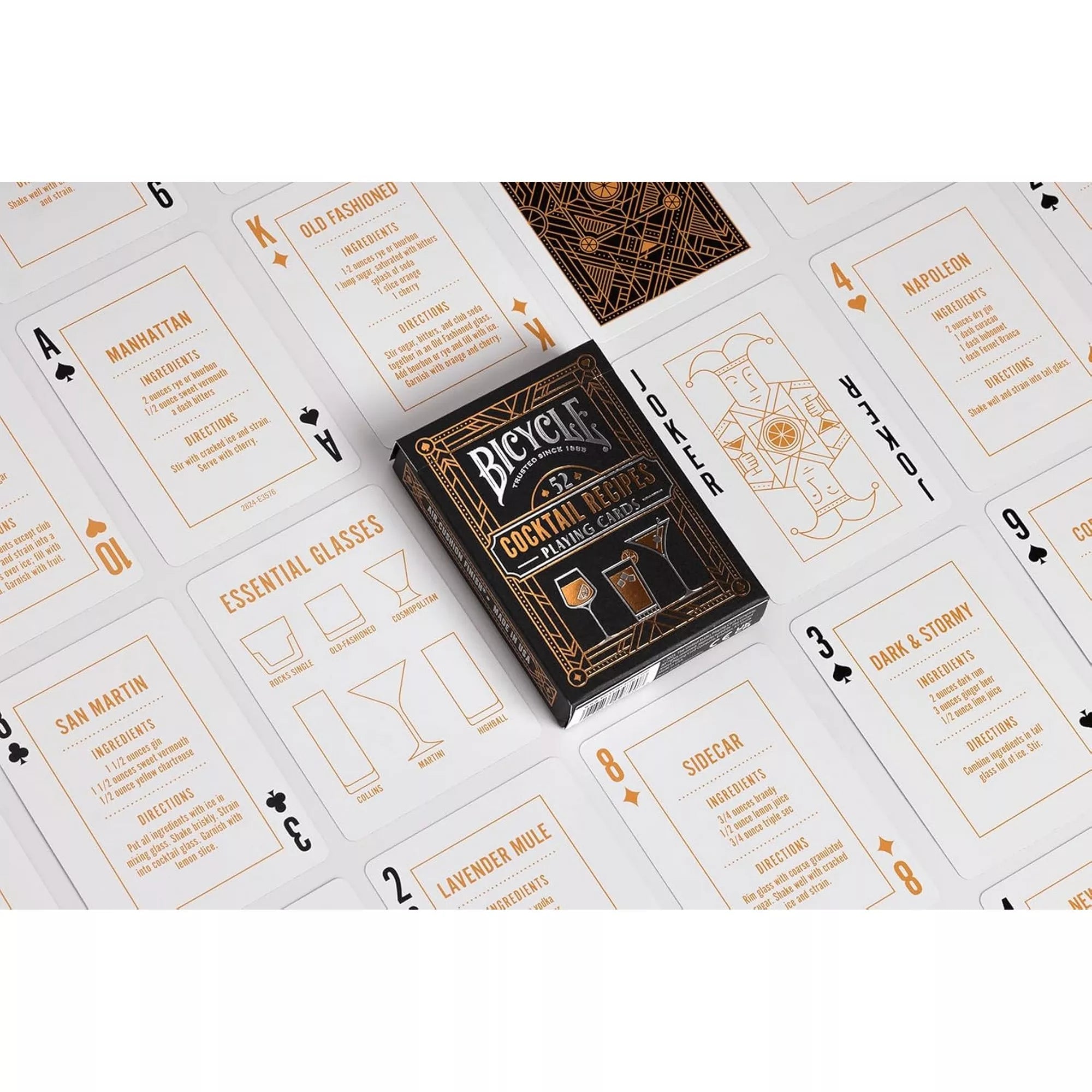 A Bicycle 52 Cocktail Recipes kártyapakli kirakott lapokkal, amelyeken koktélreceptek, hozzávalók és elkészítési útmutatók olvashatók, a középen elhelyezett dobozzal.