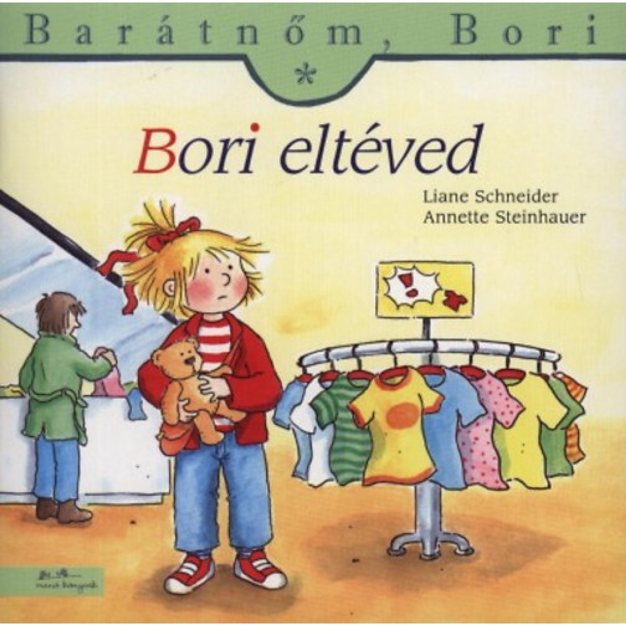 „Bori eltéved” borító – Bori egy ruhaboltban áll tanácstalanul, kezében a plüssmackóját szorongatja. A háttérben színes gyerekruhák lógnak egy kör alakú állványon, miközben Bori aggódva tekint körbe, keresve az ismerős arcokat.