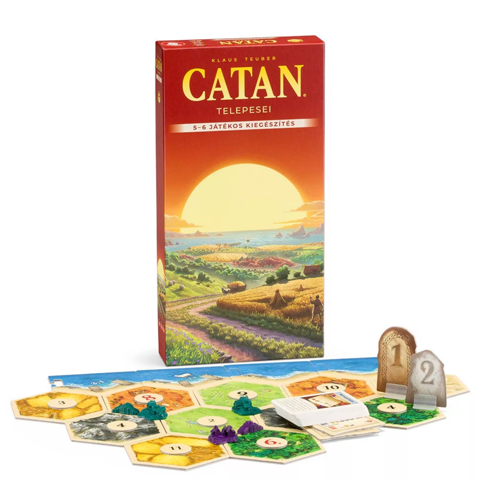 A Catan telepesei – 5-6 fős kiegészítő magyar nyelvű kiadásának doboza naplementés tájképpel, előtte hatszögletű mezőkből álló játéktábla, kártyák, fafigurák és győzelmi pontjelzők elrendezve az asztalon.