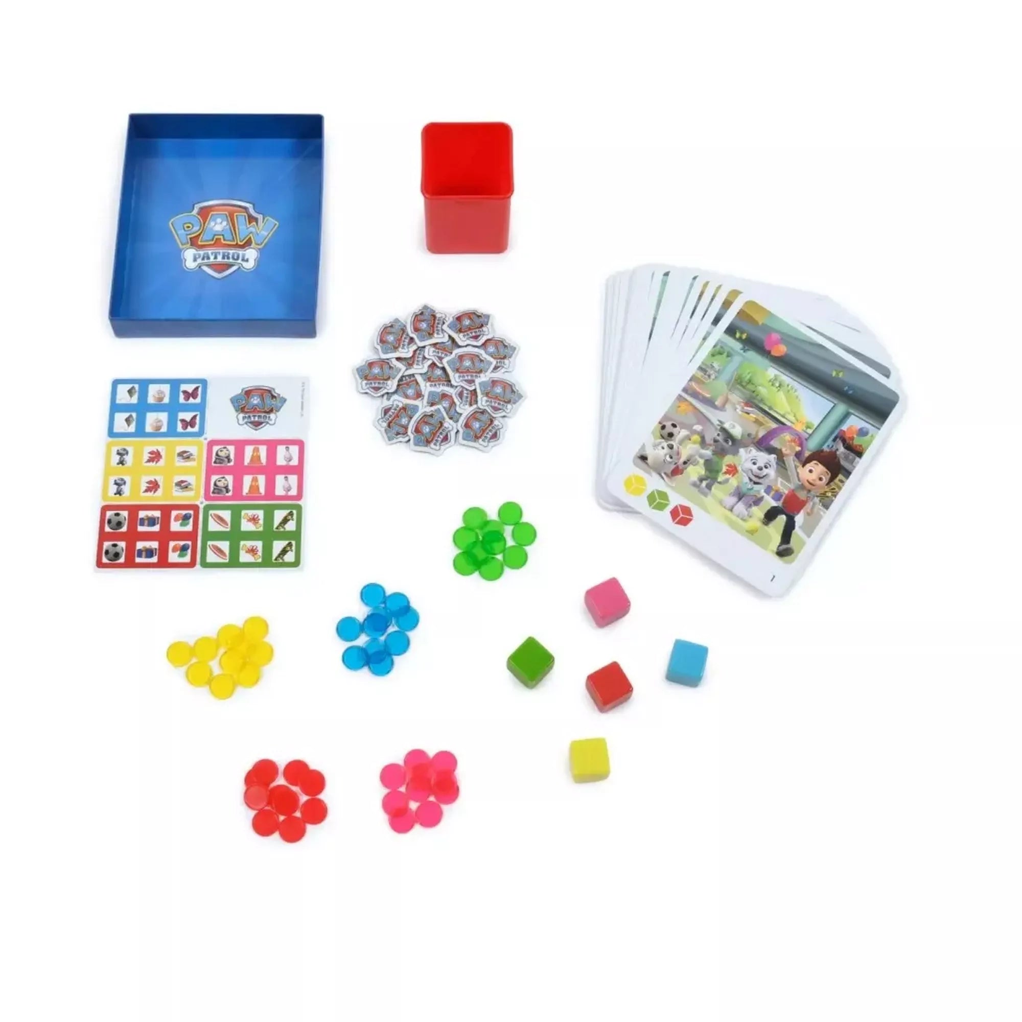 A Mancs Őrjárat Finders Keepers társasjáték elrendezett elemei: színes dobókockák, karakterkártyák pálmafás háttérrel, korongok és a piros tárolódoboz.