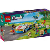 A LEGO Friends Elektromos autó és töltőállomás (42609) színes doboza, amely a 170 darabos készletet ábrázolja Nova és Zac karaktereivel. A háttérben természetes környezet, szélkerekek és zöld dombok láthatók, miközben a sportautó a töltőállomásnál áll.