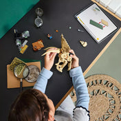 Gyermek építi a LEGO Jurassic World Triceratops-koponyát (76969), a mellékelt LEGO Builder alkalmazást használva intuitív útmutatóként.