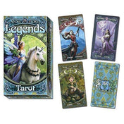 A képen az Anne Stokes Legends Tarot csomag és néhány kártyalap látható. A doboz elején egy egyszarvú és egy szárnyas tündér szerepel, varázslatos erdei háttérrel. A kibontott kártyákon részletgazdag fantasy illusztrációk jelennek meg: például a High Priestess lapján egy harcias női alak, míg a Pentacles lapján egy lila ruhás tündér látható. A The Fool lap egy vidám manót ábrázol, aki gombákon ül, körülötte zöld erdei környezet. A hátoldal mintázata világoskék-arany színvilágú.