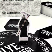 Az Aki hülye, haljon meg! társasjáték kaszás figurája a fekete játéktáblán.