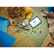 Egy gyermek a LEGO City Rendőrségi motorcsónak (60456) hajó fedélzetét építi, mellette tablet és a készlethez tartozó figurák és elemek.