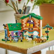 LEGO Friends Pónifarm és istálló (42654) készlet egy asztalon elhelyezve, pónikkal, kocsival és karakterekkel játék közben.