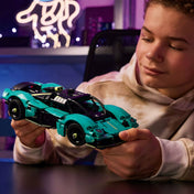 Egy fiú a LEGO Technic Aston Martin Valkyrie (42208) megépített modelljét tartja a kezében, színes háttérrel és lágy fényekkel, kiemelve az autó formavilágát.