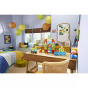 Modern gyerekszoba színes dekorációval, az íróasztalon a MAGNA-TILES City Center város építménye látható útelemekkel és autókkal, inspiráló játékos környezetben.