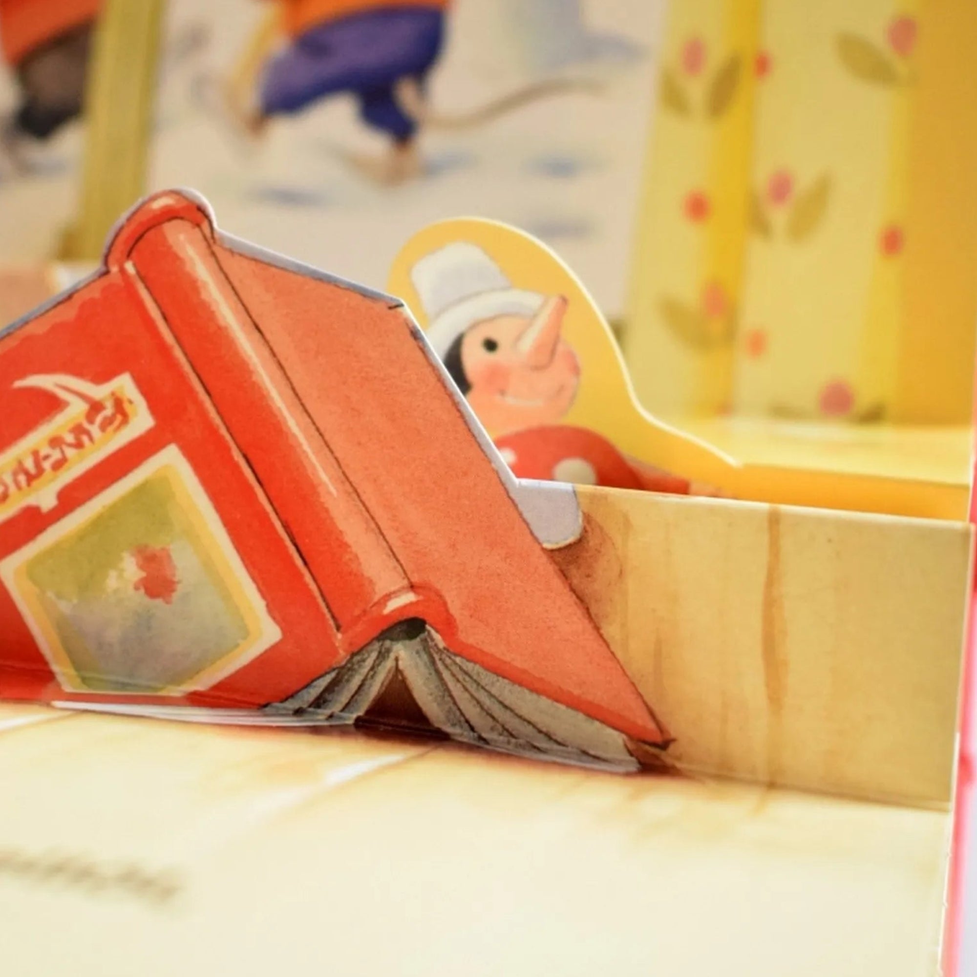 Mesél az erdő – Karácsony könyvrészlet – Közelről látható egy piros könyv és egy mesefigura, részlet a 3D illusztrált oldalak egyikéről.