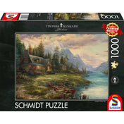 „Schmidt Puzzle: Thomas Kinkade, Apák napi kirándulás 1000 darabos dobozkép, festői hegyi tájjal, faházzal és folyóparti jelenettel.”