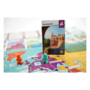 Az Utazás a Föld körül játéktábla részlete, előtérben a Halászbástyát ábrázoló kártyával és két játékos bábujával.