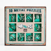A 10 Metal Puzzle Set zöld változatának doboza elölről fotózva, amelyen tíz különböző fémből készült kirakó látható zöld háttérrel, rusztikus stílusú keretben, középen a „Eureka! 3D Puzzle” logóval.