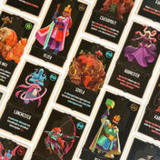 Az Uralkodó társasjáték részletgazdag kártyalapjai egymás mellett, hősök, szörnyek, mágusok és különleges képességeket bemutató fantasy illusztrációkkal.