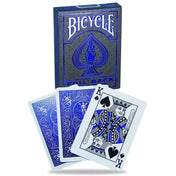 A Bicycle Foil Back Cobalt kártyapakli doboza három kirakott kártyalappal, köztük a pikk király és két fényes, kék fóliás hátlapú lap elegáns elrendezésben.