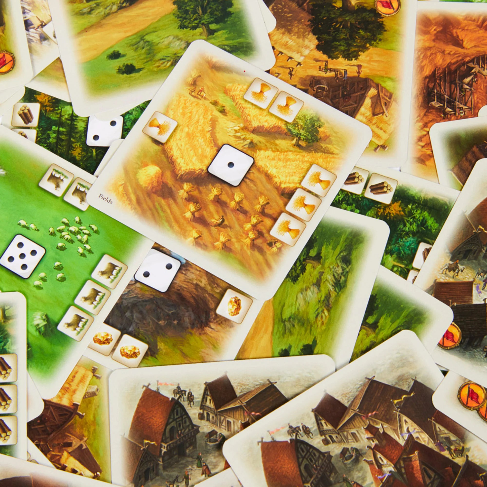 A képen a "Catan: A párbaj" társasjáték kártyái láthatóak fölülnézetben. A kártyák különböző tájakat ábrázolnak, mint például mezőket, erdőket és településeket. Minden kártya egyedi erőforrásokat, például gabonát, fákat és követ tartalmaz, amelyek felhasználásával a játékosok fejleszthetik birodalmukat.