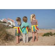 BS Catch & Snatch játék használat közben: három gyermek a tengerparton, derekukon a színes, számozott pántokkal ellátott ügyességi játékkal.

