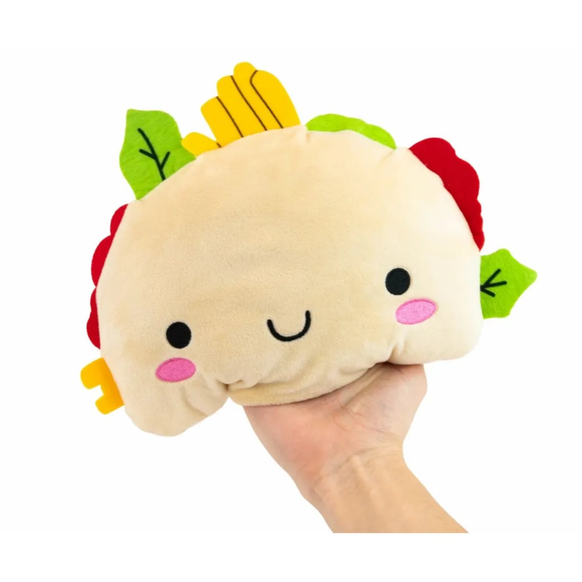 A játék aranyos, taco alakú plüssfigurája egy kézben tartva, jól látható textúrájú, bézs színű testtel, rózsaszín arcfoltokkal, fekete mosolygó arccal és zöld, sárga, piros filc hozzávalókkal a tetején.