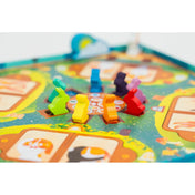 Dixit Kids társasjáték játéktáblája közelről, színes fa figurákkal és illusztrált mezőkkel.