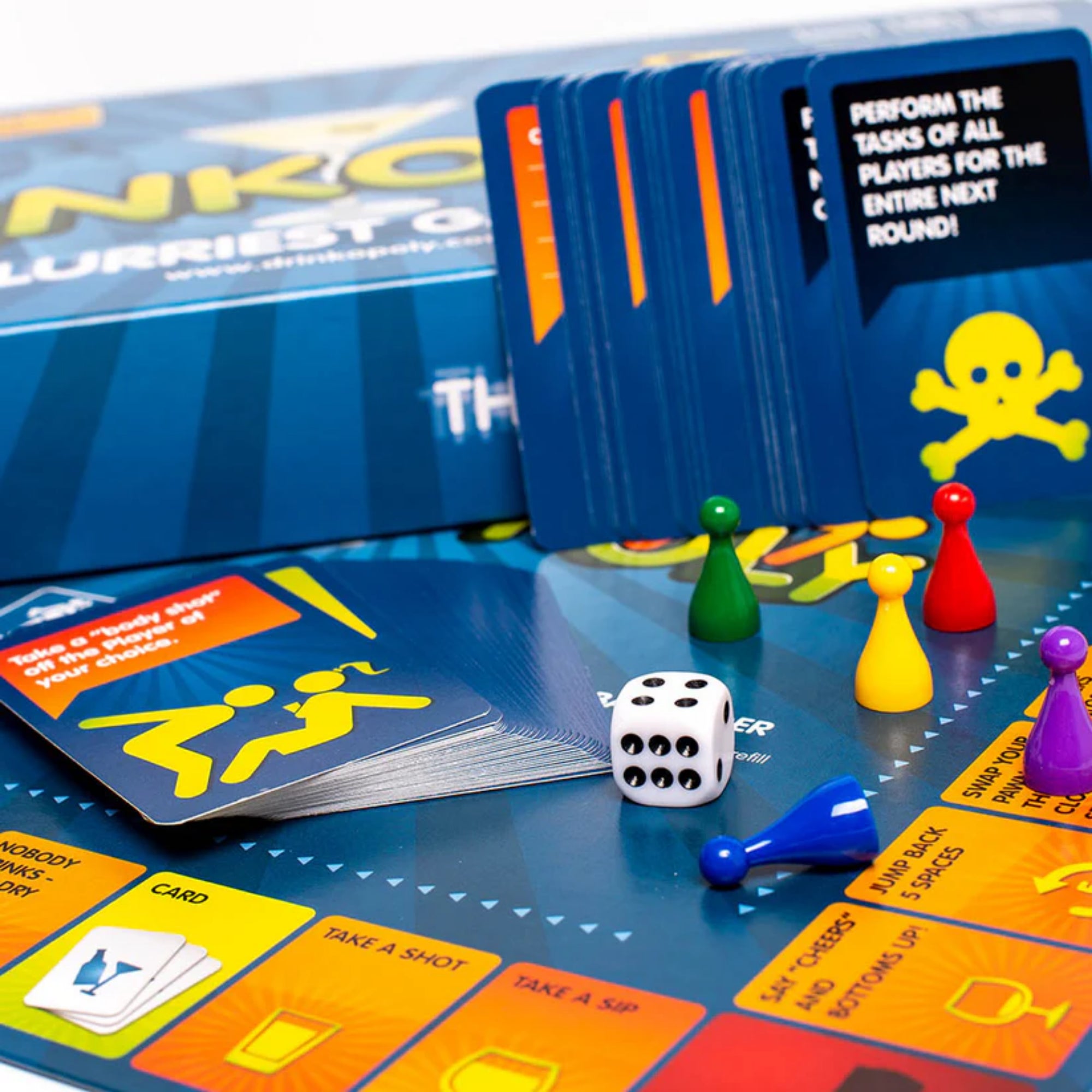 Drinkopoly társasjáték játékelemek közelről, színes játékbábukkal, fehér dobókockával, ivós feladatkártyákkal és akciókártyákkal a játéktábla egyik mezőjén.