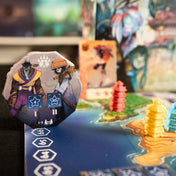 Ethnos – 2. kiadás társasjáték jelenet közelről: karakterlap és színes pagoda figurák a játéktáblán, részletgazdag illusztrációval.