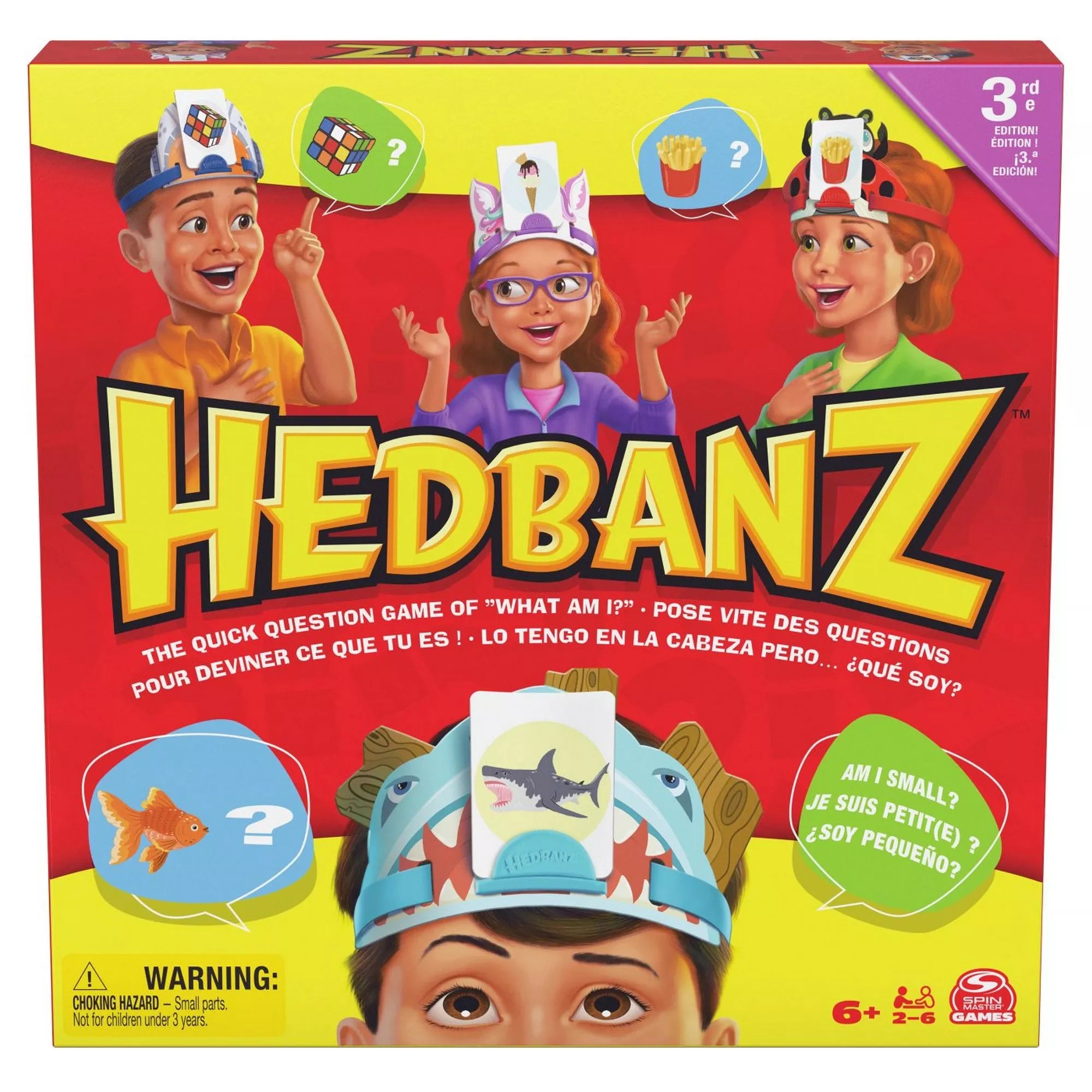 A Hedbanz társasjáték színes doboza, rajta gyerekek láthatók fejpántokkal és kártyákkal a fejükön, a játék logója és leírása jól kivehető.