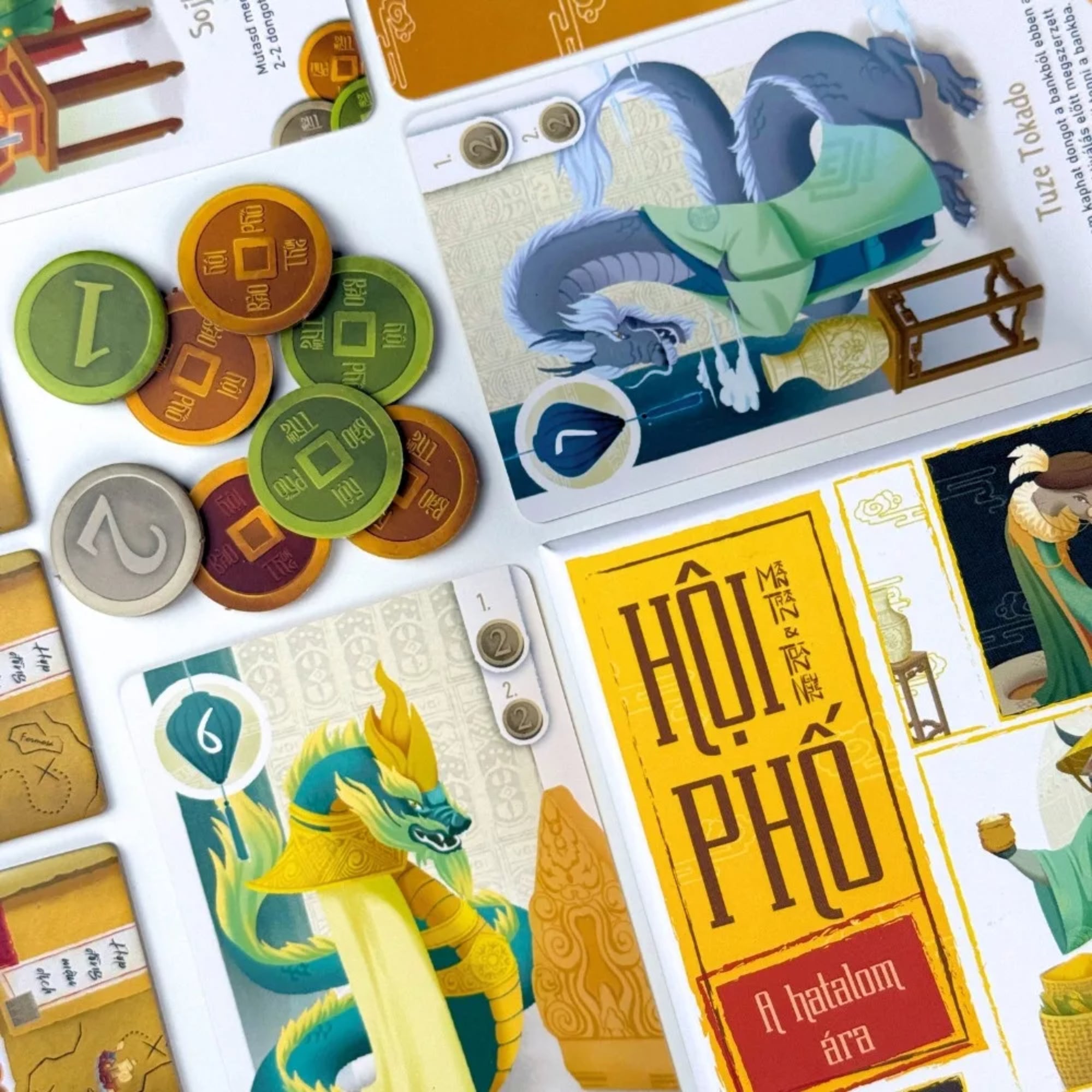 Hội Phố – A hatalom ára társasjáték kártyái és dong érméi közelről, sárkányos és kereskedős illusztrációkkal.