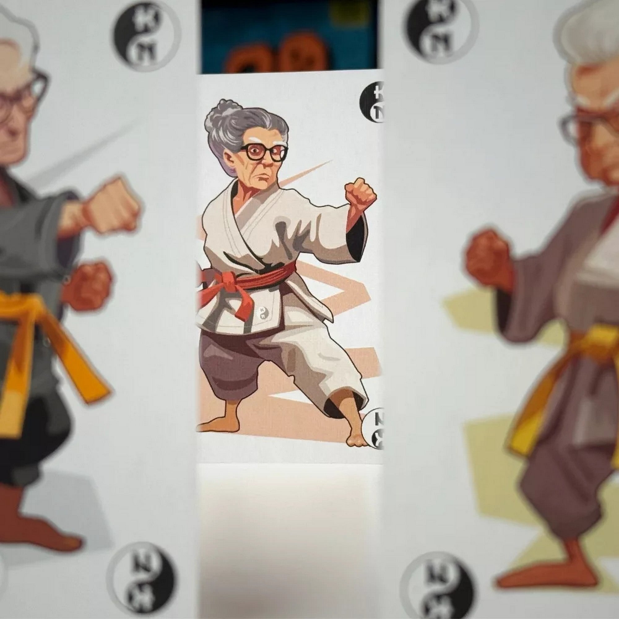 Karate Nagyik társasjáték kártya közelről, karate ruhás nagymama harci pózban, részletes grafikai stílusban.
