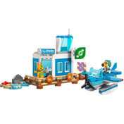A LEGO Animal Crossing: Repülj a Dodo Airlines fedélzetén (77051) szett oldalsó nézete, fókuszban a kék-fehér reptéri épület és a vízen úszó repülőgép.