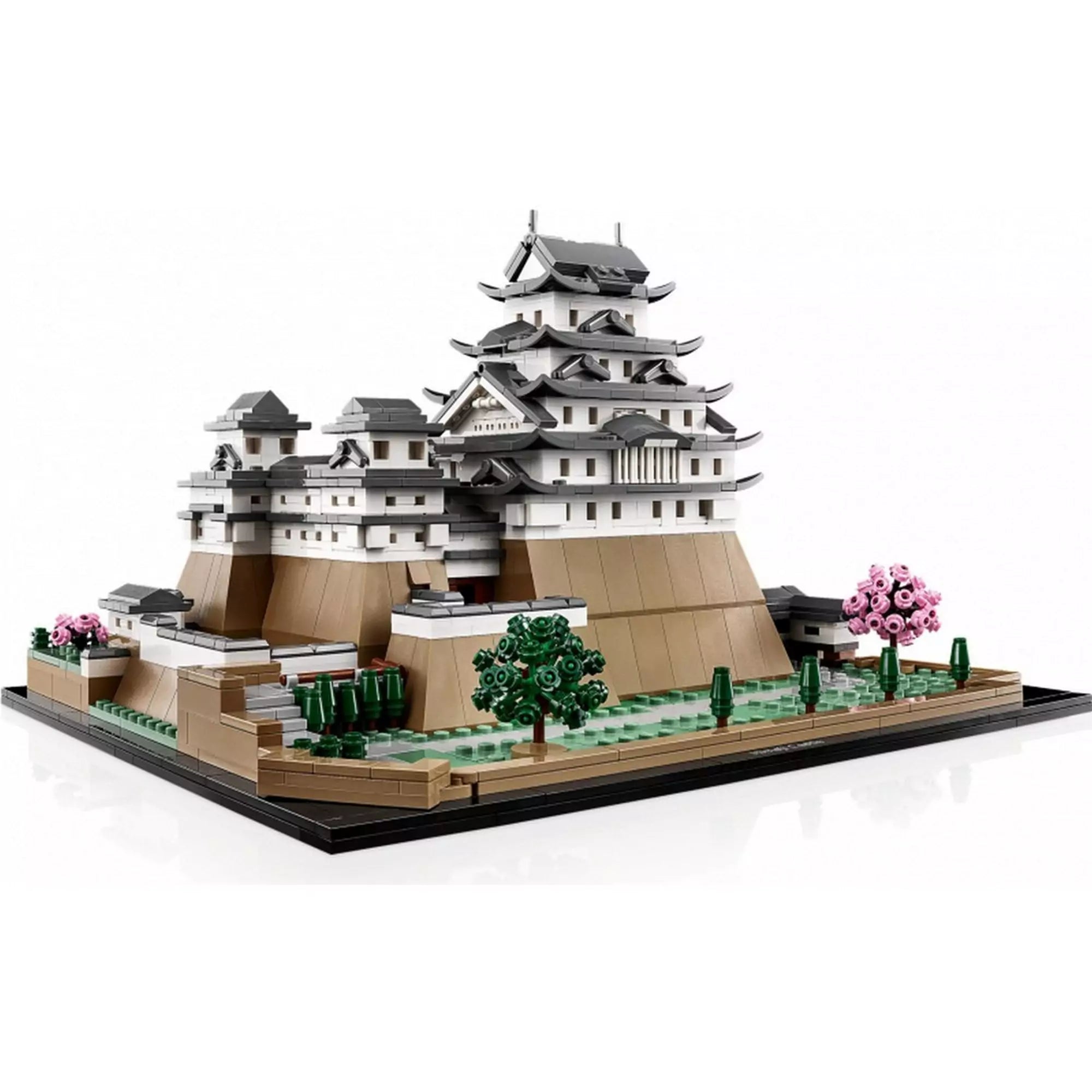 A LEGO Himedzsi várkastély (21060) modellje oldal nézetből, a fehér falú, szürke tetős főépülettel és zöldellő kertekkel, rózsaszín cseresznyefákkal.