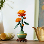 A LEGO Botanicals 10368 Chrysanthemum készlet teljes építménye egy fa asztalon elhelyezve, elegáns dekorációs környezetben.