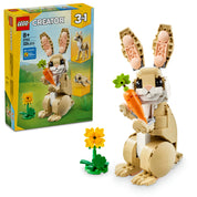 A LEGO Creator Aranyos Nyuszi 31162 készlet képe, bemutatva a felépített nyuszimodellt, amint egy nagy narancssárga répát tart. A nyuszi fehér és bézs színekben pompázik, nagy mozgatható fülekkel és kifejező szemekkel. A doboz a háttérben látható, amin két további állatmodell, egy láma és egy fóka, szintén megjelenik. A kép előterében egy virág díszít, ami a természetközeli témához kapcsolódik.