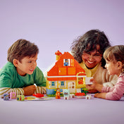 Két gyermek és egy felnőtt együtt játszik a LEGO DUPLO Bluey családi ház készlettel.