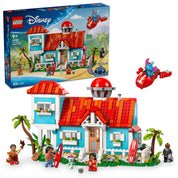 A képen a LEGO Disney Lilo és Stitch Tengerparti Háza (43268) készlet látható, amely egy részletgazdag, kétemeletes tengerparti otthont tartalmaz. A kék és piros színvilágú ház ikonikus elemekkel van díszítve, beleértve a verandát, a szörfdeszkákat és a trópusi növényeket. A készlethez öt LEGO minifigura is tartozik: Lilo, Stitch, Nani, David és Mr. Bubbles, valamint Lilo babája, Scrump.