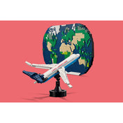 A LEGO Family A nyaralás pillanatai (41838) készlet illusztrációja, amelyen a repülőgép a Földet szimbolizáló LEGO alaplap előtt lebeg piros háttérrel.