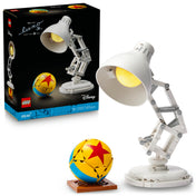 A LEGO Ideas Disney Pixar Luxo Jr. (21357) készlet összeépített modellje egy fehér, mozgatható íróasztali lámpával és egy sárga-kék labdával, a háttérben a termék doboza látható.