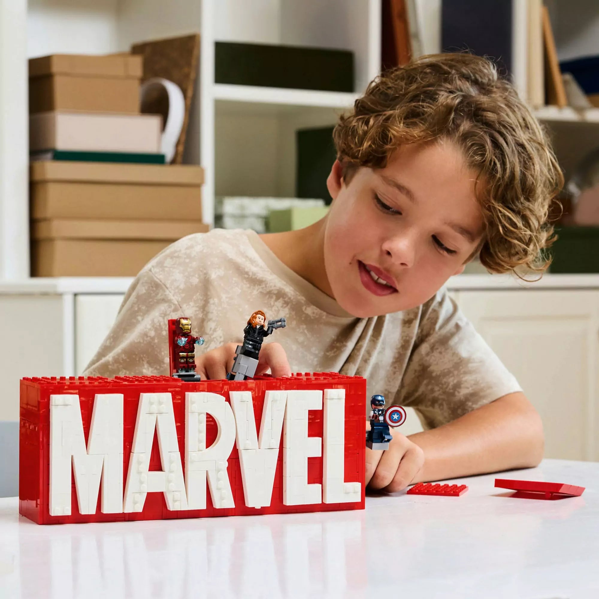 Fiú játszik a LEGO Marvel MARVEL logó és minifigurák (76313) szettel, Hulk, Vasember és Amerika Kapitány életre kelnek.