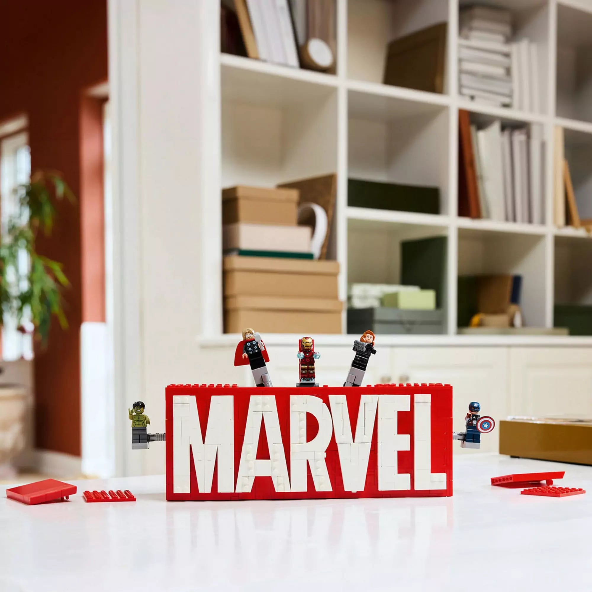 A kész LEGO Marvel MARVEL logó és minifigurák (76313) szett, minifigurák kitörnek a logóból, bemutatva az akciódús funkciókat.