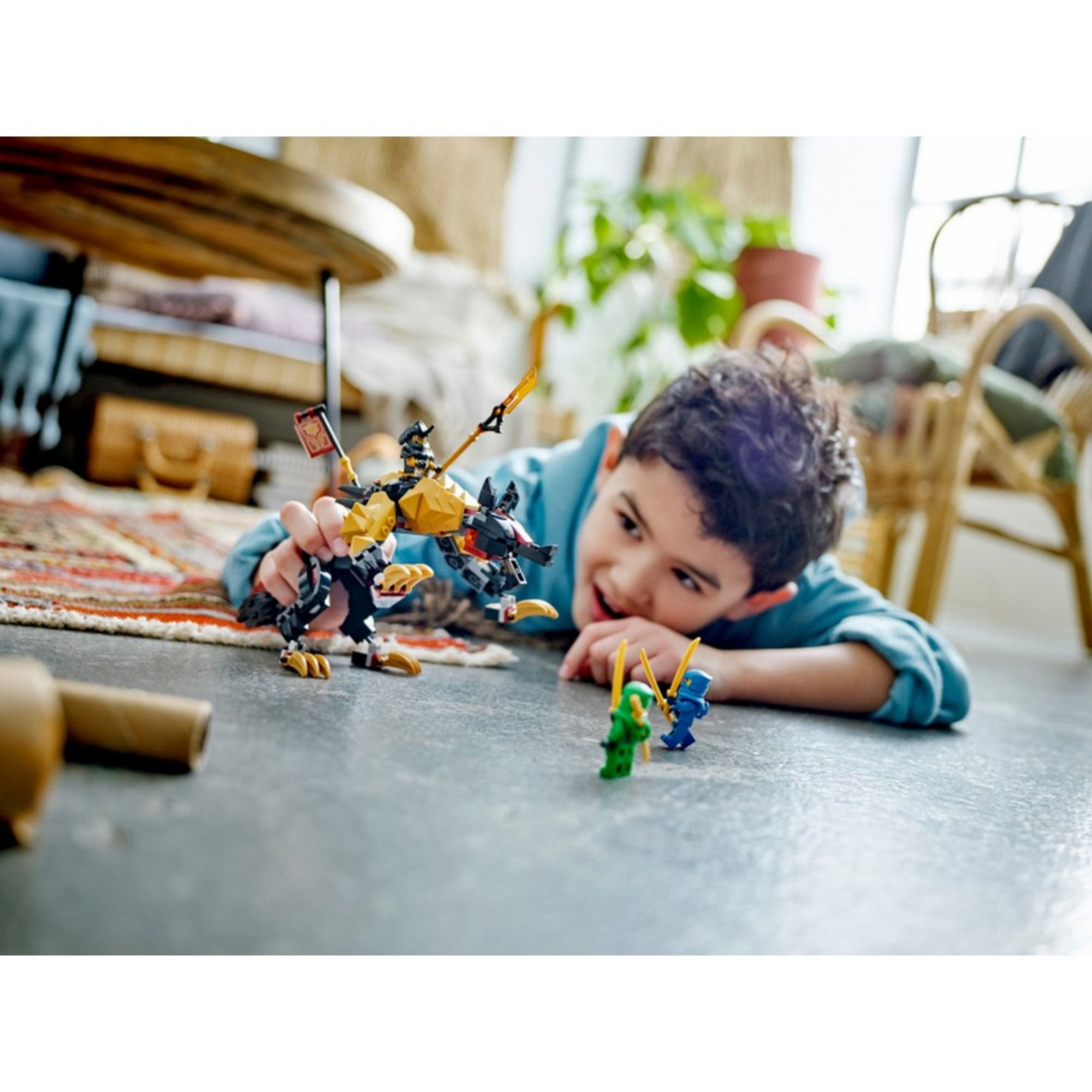 Egy kisfiú játssza újra a nindzsák és a gonosz vadász küzdelmét a LEGO Sárkányvadász kopó készlettel egy nappaliban.