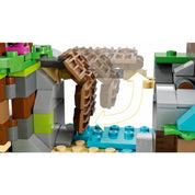 Közelkép egy barna, mozgatható függőhídról a LEGO 76992-es készletből, amely víz fölé hajtható, zöld sziklákkal és színes elemekkel körülvéve.