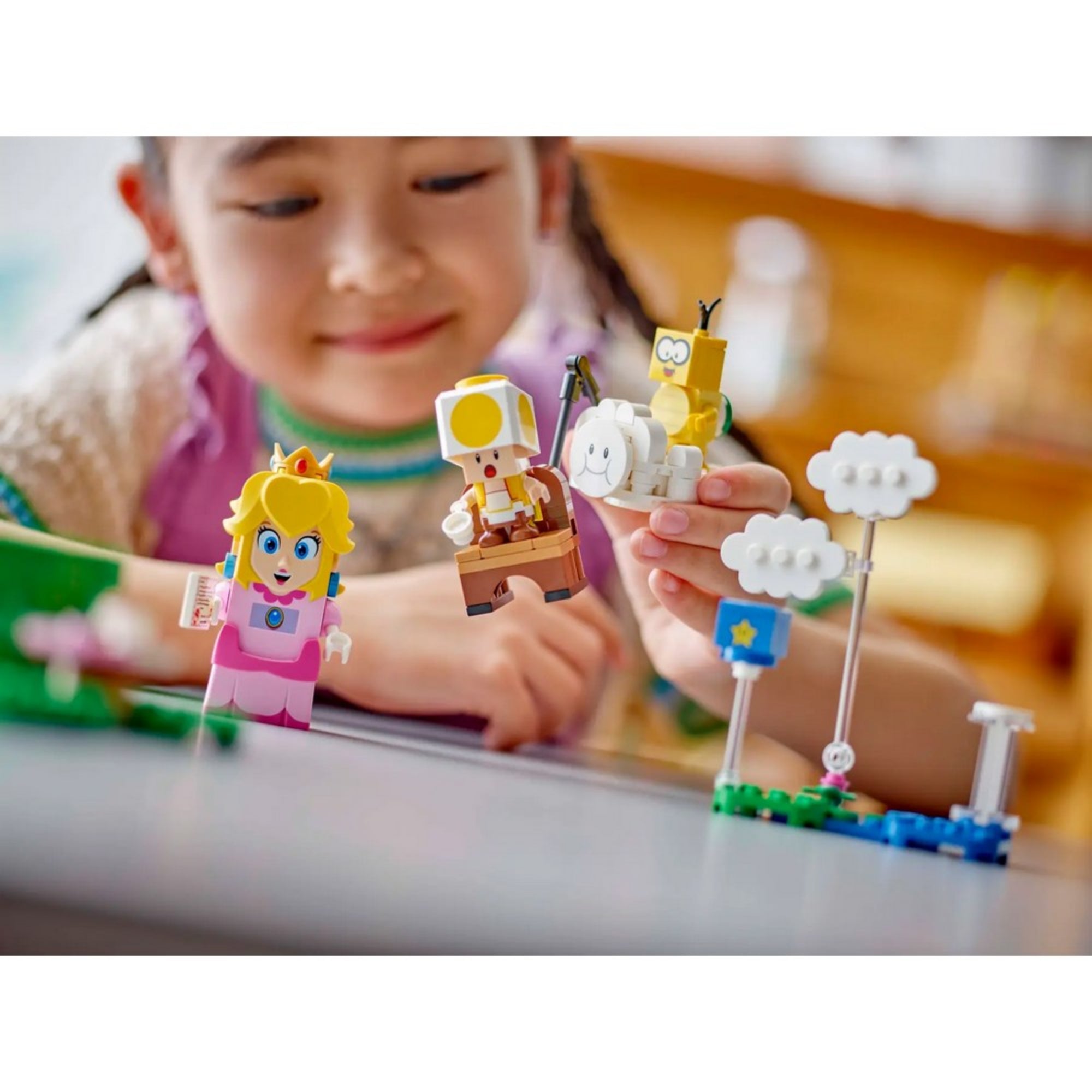 LEGO Super Mario Kalandok az interaktív LEGO Peach figurával (71441) – egy mosolygó kislány kézben tartja a LEGO Peach és Yellow Toad figurákat játék közben.