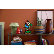 A pixelgrafikás LEGO Mario és Yoshi figura (71438) kiállítva egy szobapolcon könyvek, vázák és lakásdekorációk mellett.