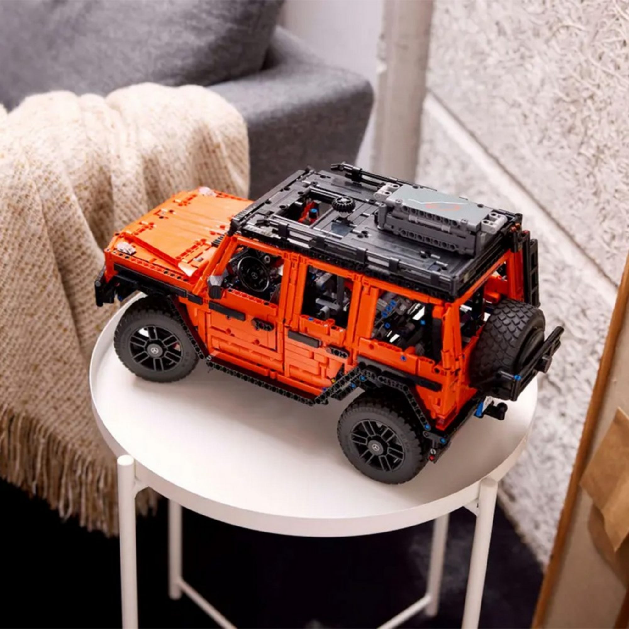 LEGO Technic Mercedes-Benz G 500 PROFESSIONAL Line modell kiállítva egy kis kerek asztalon, modern enteriőrben.