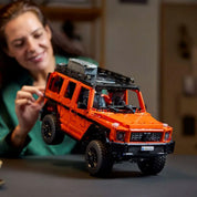 LEGO Technic Mercedes-Benz G 500 PROFESSIONAL Line modell megemelve, építés közbeni jelenet egy női kézzel, fókuszban a jármű felfüggesztése.