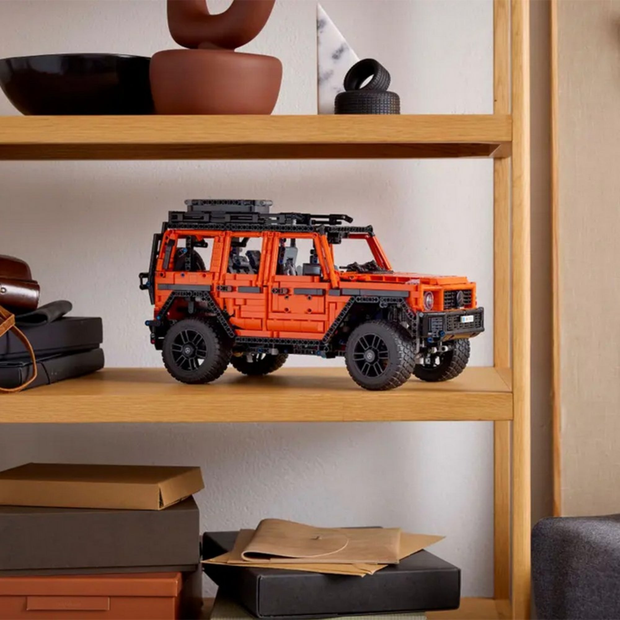LEGO Technic Mercedes-Benz G 500 PROFESSIONAL Line terepjáró egy fa polcon kiállítva, háttérben lakberendezési tárgyakkal.