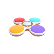 A Szólicit társasjáték eszköze felülről nézve, négy színes nyomógombbal (piros, sárga, kék, lila) és egy középen elhelyezkedő fehér vezérlőrésszel. Az interaktív egység világos háttéren látható.