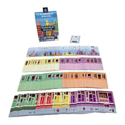 A Táncoló Házak társasjáték kártyái kiterítve: tető-, emelet- és földszintlapok különböző színekben, a dobozzal a háttérben.