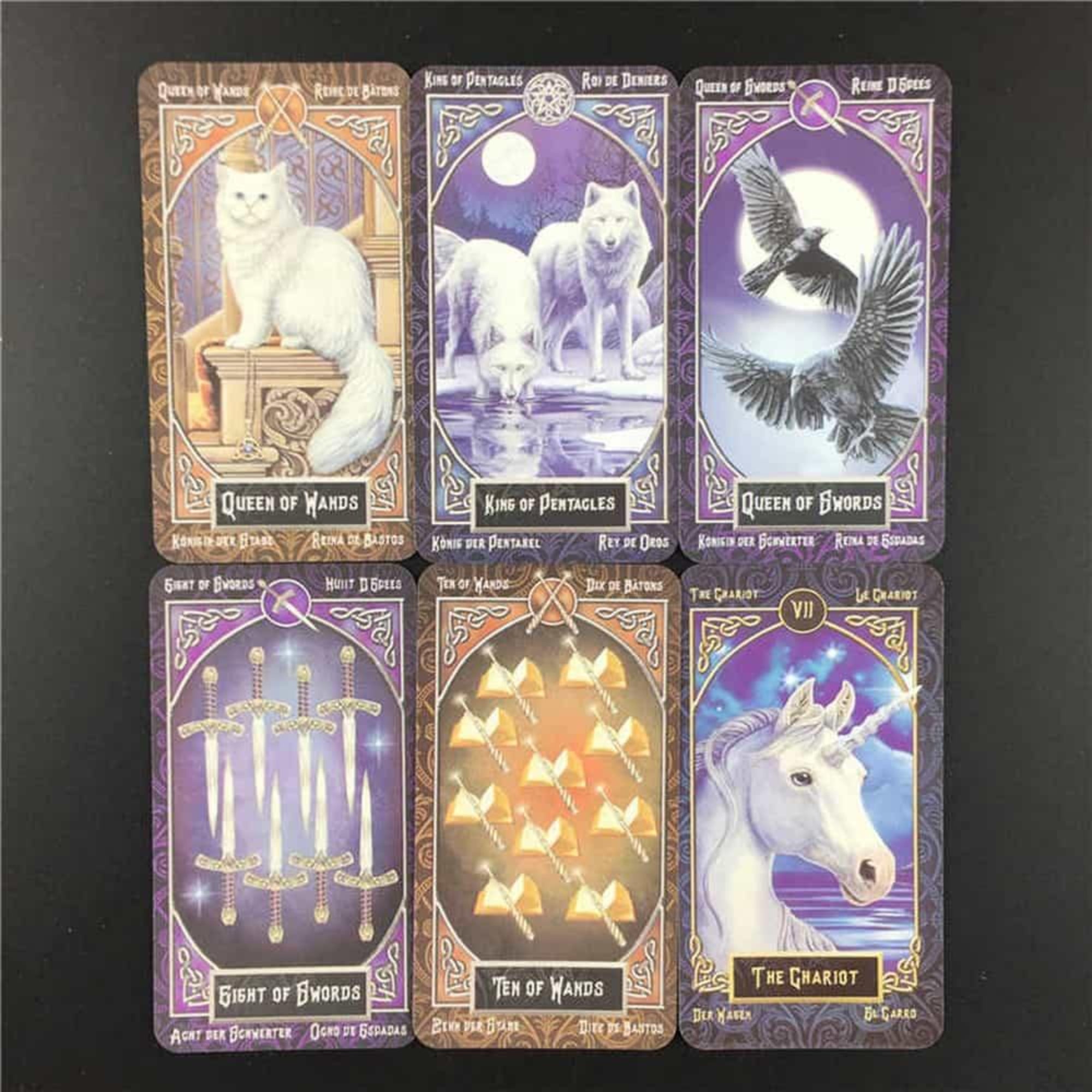 A képen a Tarot Familiars kártyacsomag néhány lapja látható, köztük a Botok Királynője, az Érmék Királya, a Kardok Királynője és a Diadalszekér. A kártyákat misztikus állatok, például fehér macska, farkasok, hollók és unikornis díszítik.