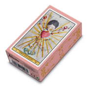 A képen a Tarot de Luz kártyapakli díszdoboza látható, amelyet pasztell rózsaszín szín és arany díszítés jellemez. A doboz tetején a "Two of Cups" (Kelyhek kettes) kártya grafikája szerepel, mely egy szívből kiáradó sugárzást és szeretetteljes motívumokat ábrázol. A finom, akvarell stílusú illusztrációk és az elegáns kialakítás romantikus és álomszerű hangulatot kölcsönöznek a paklinak.