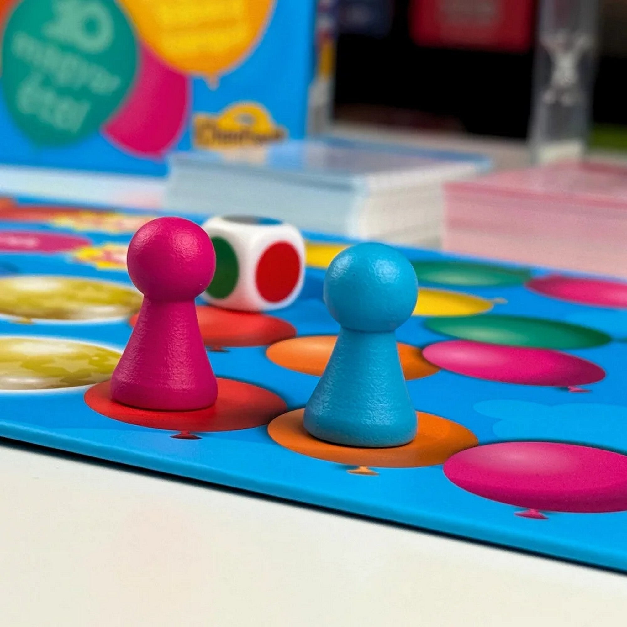 Junior Tension társasjáték játéktábla részlete színes mezőkkel, két bábuval és dobókockával, játék közbeni hangulatot bemutatva